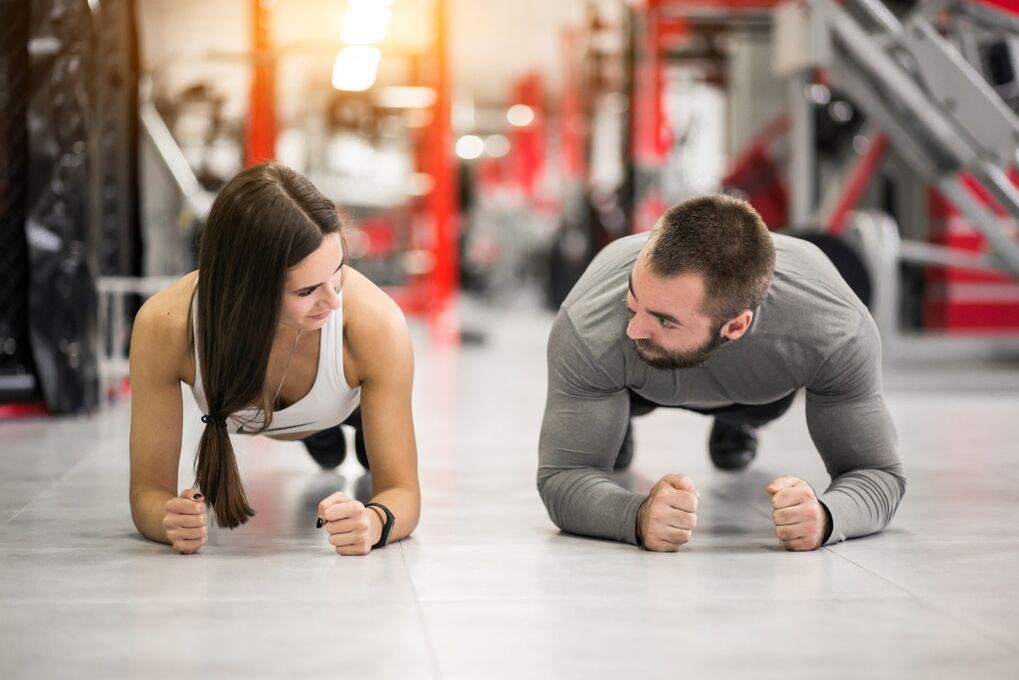Muž a žena provádějí cvik Plank, určený pro všechny svalové skupiny